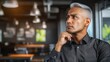 © Thavesak - Thoughtful man in black shirt contemplating in modern cafe setting