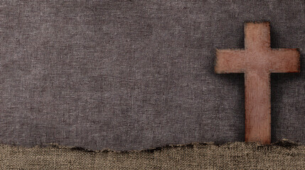 Poster - Aged wooden cross on textured fabric background.
