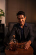 © aekachai - Businessman holding a glass of whiskey in a restaurant sitting on a sofa