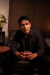 © aekachai - Businessman holding a glass of whiskey in a restaurant sitting on a sofa