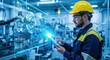 © Chanthakan - Industrial engineer wearing safety helmet and glasses operates advanced digital interface in modern factory, using tablet to monitor automated machinery and futuristic technology