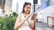 © dodotone - Happy asian woman city lifestyles using smartphone internet and shopping at outdoors department store