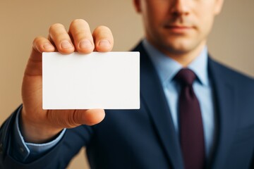 Poster - Businessman holding blank business card in hand, close-up shot with light background, useful for branding or promotional design templates.