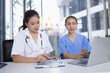 © SOMKID - Female doctor and nurse working together with clipboard and laptop for in modern clinic.