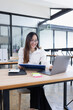 © SOMKID - Asian business woman working with laptop and analyzing financial charts at a desk.