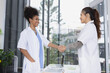 © SOMKID - Two female doctors shaking hands in meeting room at hospital, Healthcare and medical concept.