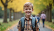 © Kseniia - smiling schoolboy with a backpack enjoying a walk in a park during autumn