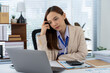 © Kritdanai - Businesswoman in Thought: A focused businesswoman sits at her desk, laptop open, pondering the day's challenges, her expression suggesting both deep concentration and mild stress.