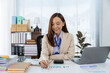 © Kritdanai - Focused professional at desk: An attractive business professional concentrates on financial documents at her desk. The natural light highlights the focused expression and her dedication.