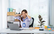 © Kritdanai - Overwhelmed in the Office: A woman, distressed by a stressful work environment, clutches her head, encapsulating the pressures of a demanding work life.