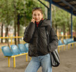 © tan4ikk - Happy Girl Talking On The Phone While Waiting For A Bus At The Station