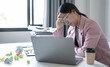 © Orathai - Working Asian women feel stressed, tired from work, migraine headaches from hard work while working at the office