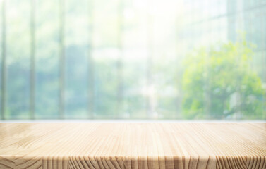 Wall Mural - Empty of wood table top on soft blur of big glass window from office building with grren garden background.not ai generated
