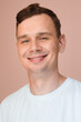 © shotmatic - Smiling young man in a white t-shirt on a soft pink background. Friendly and relaxed portrait.