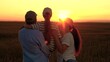 © Victoriia - Loving parents baby girl in arms enjoying nature on wheat field in sun. Dad mom child daughter hugging happily at sunset. Happy farmer family on field. Happy future dream concept. Parents, girl child