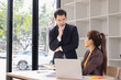 © SOMKID - Two Asian business people with analyzing financial report working together in office.