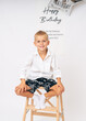 © Elena - Smiling Birthday Boy on Stool with Festive Backdrop