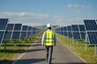 © Huu da - employee walking at a solar power farm, wearing safety vest and helmet . solar panel installation