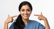 © Artem Zatsepilin - smiling indian woman in blue attire pointing at her bright smile against plain white background. concept of happiness, positivity, self-confidence. dental health, wellness, lifestyle, stomatology.