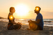 © New Africa - Couple meditating in Lotus pose on beach. Glowing bubbles representing chakras