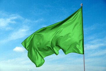Wall Mural - green flag waving against blue sky outdoors
