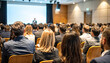 © miracle - Back view of people in audience at the conference hall, Speaker giving a talk in conference hall at business event