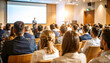 © miracle - Back view of people in audience at the conference hall, Speaker giving a talk in conference hall at business event