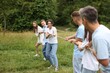 © New Africa - Team building. Group of happy people playing tug of war with rope outdoors