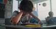 © Framestock - Stressed Primary School Boy Sitting Alone at Desk in Classroom While Aggressive Classmates Abusing Him, Throwing Papers and Laughing. School Bullying, Peer Harassment and Toxic School Environment.