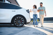 © Serhii - Couple walking near electric car charging at home