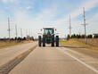 © Carrie - Tractor driving down a two lane asphalt road. Viewed from behind