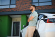 © Serhii - Man waiting while charging electric car in front of his modern house