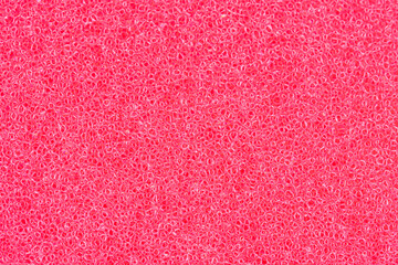 Bright pink sponge texture close-up. Macro shot of porous synthetic foam material, soft and flexible. Abstract pattern background for cleaning, hygiene, bathroom or design use. Vibrant color texture.