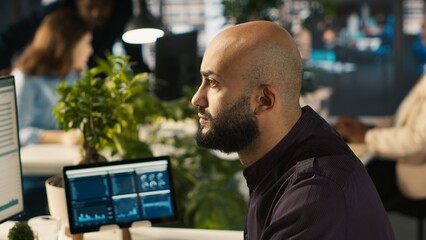 Poster - Startup staff member working to hit key performance targets for revenue, profitability and operational efficiency. Employee at computer desk doing research analysis, camera A close up