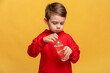© Irina Mikhailichenko - Happy little boy drinks water for health on yellow background. The child is opening a bottle of water. A kid with a plastic bottle. Children's activity and energy, generation Z. body hydration concept