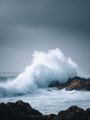  Dramatic seascape capturing a powerful wave crashing against rocky shores. Evokes strength, natures force, and resilience. Ideal for backgrounds, editorials, or symbolic content.