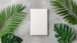© merkuribius - Blank white book surrounded by tropical leaves on a gray concrete surface
