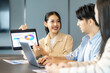 © Jestercine - Asian woman presenting colorful charts during a team meeting, discussing ideas and performance metrics to support the business strategy in a collaborative business strategy session