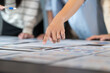 © Jestercine - Close-up of a hand pointing at printed charts during a team meeting, showing collaboration and active discussion in a professional environment focused on chart.