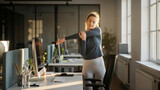 Young businesswoman doing stretching exercises beside her desk in bright modern office
