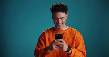 Phone, happy and man in studio for social media, online chat and text message on mobile app. Space, typing and person on smartphone for website, internet connection and contact on blue background