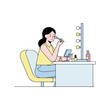 © Vincenzo - Woman applying makeup at her vanity. Woman applying makeup in front of her vanity with a hand mirror and various beauty products arranged on table. The woman applying makeup is preparing for day out,