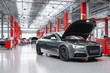 © ttonaorh - Car repair shop, a gray car with an open hood on the right side of an automotive workshop in a modern style with red pillars, cars standing at their stations for servicing. The background is blurred.