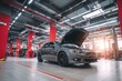 © ttonaorh - Car repair shop, a gray car with an open hood on the right side of an automotive workshop in a modern style with red pillars, cars standing at their stations for servicing. The background is blurred.