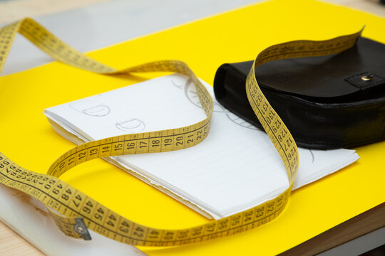 A bright yellow measuring tape is laying on top of a notebook