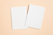 © nikavera - Two blank white sheets of paper on beige background, copy space for design purposes, ideal for invitation mockup presentations and creative projects