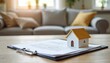 © Vadym - Miniature house on property title documents with clipboard on wooden table. Background shows blurred living room interior. Symbolizes home buying, real estate investment, legal agreements, contracts.