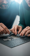 Poster - Close-up of hands assembling dark gray jigsaw puzzle pieces, symbolizing teamwork, problem-solving, and collaboration