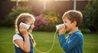 © ngamaz - Two happy children talking through tin can telephones in a sunny garden