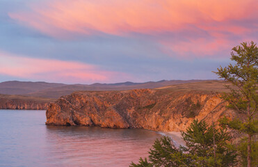 Wall Mural - Beautiful bright sunset sky with pink clouds over shore of Baikal Lake after rain. View of Small Sea and steppes of Olkhon Island. Scenic landscape. Natural background. Summer travel and recreation
